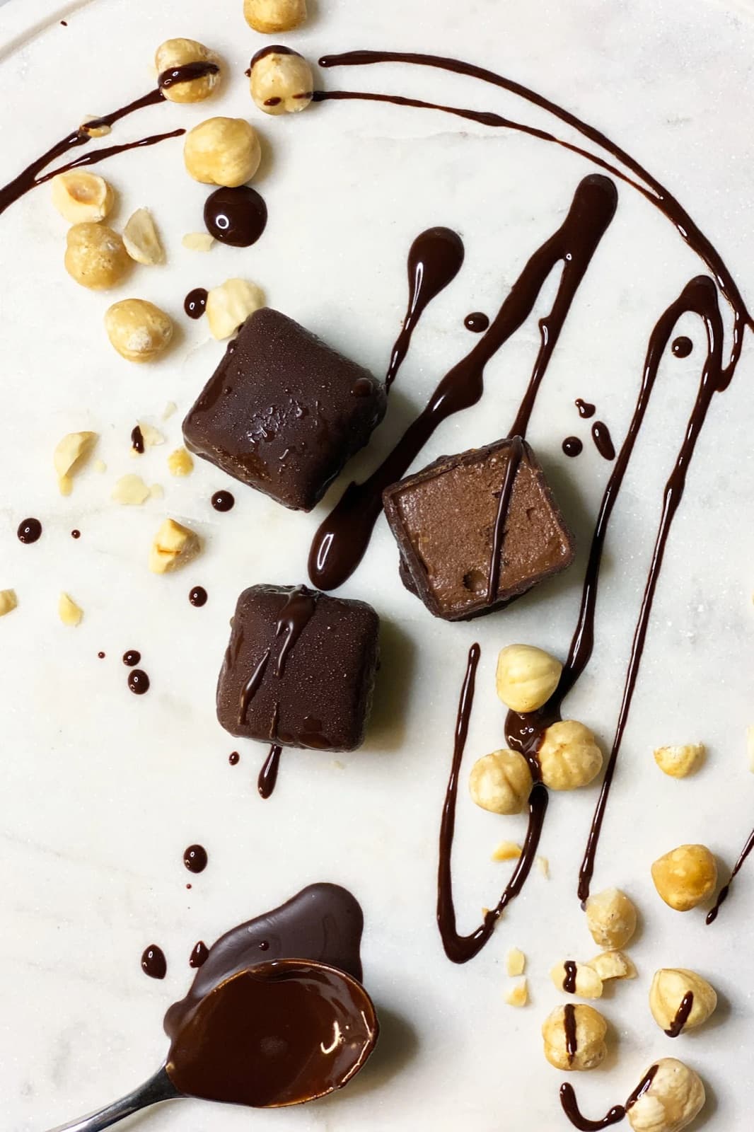 Paccari chocolate cubes with melted chocolate and hazelnuts on marble